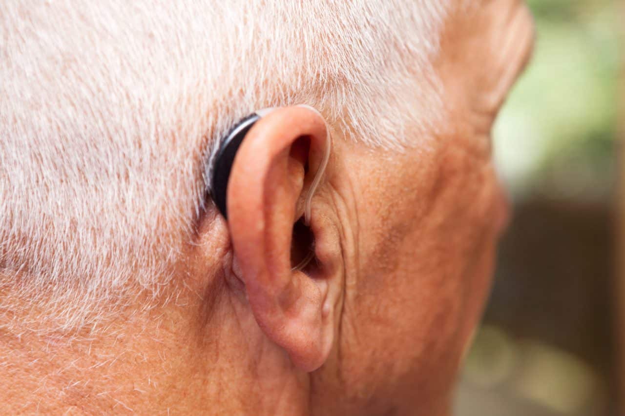 Senior man wearing a small behind-the-ear hearing aid.