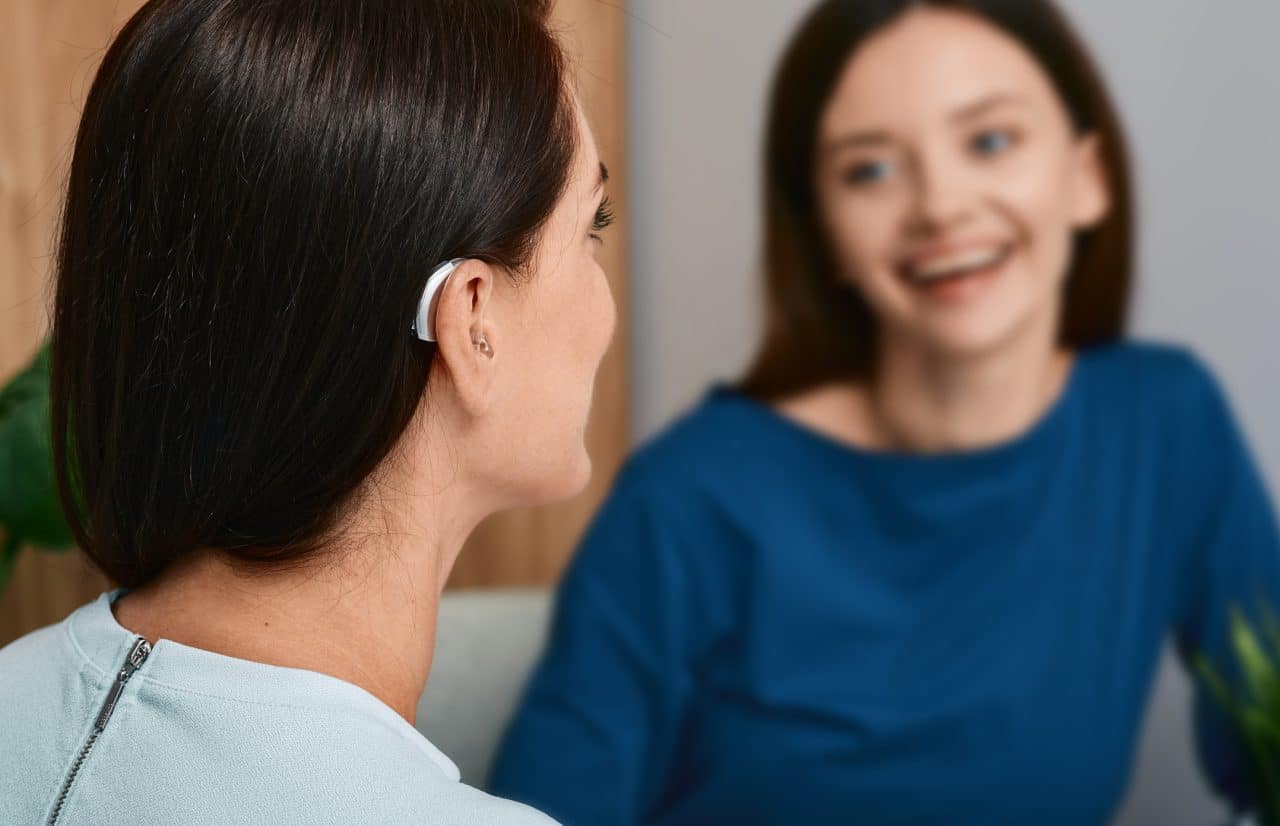 Woman with a hearing aid chats with her friend.