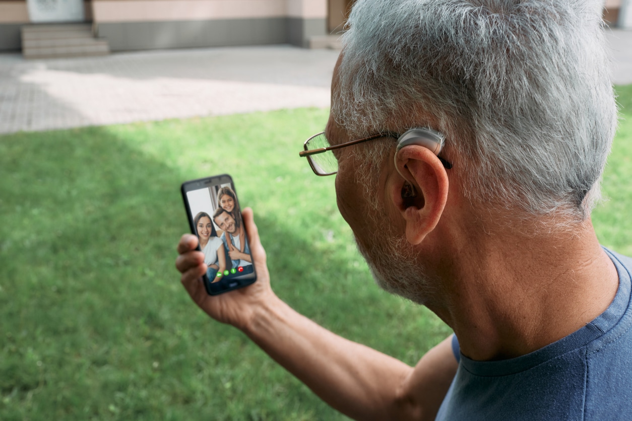 Man with hearing aid video chatting with his family.